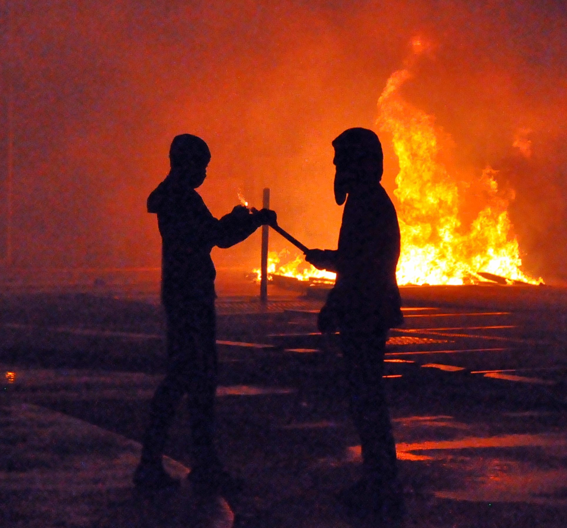 Two silhouetted figures in front of a fire during unrest in Planoise, Besançon, in 2023