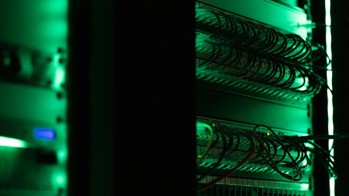 A rack of equipment in a dark room, with green status lights