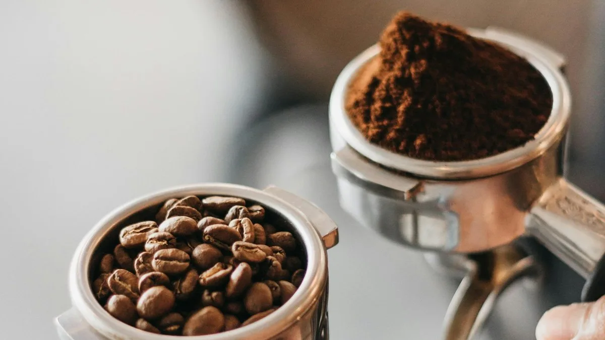Two portafilters side by side: one holding whole coffee beans, the other ground coffee