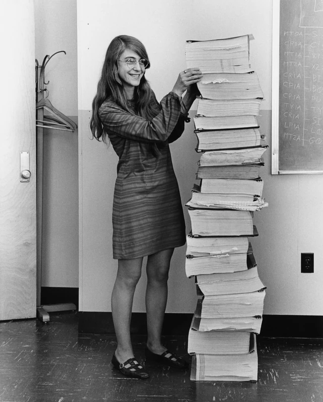 Margaret Hamilton in 1969, standing next to a stack of printed listings taller than she is.